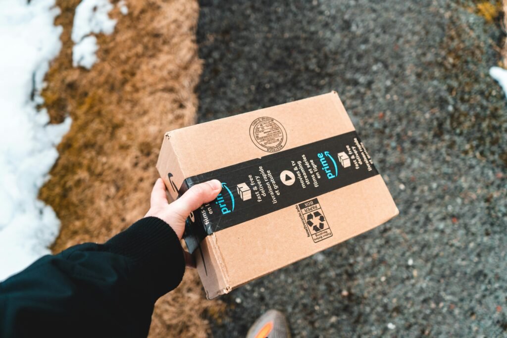 pexels photo 16158539 16158539 A person holding a cardboard Amazon Prime package on a snowy urban sidewalk.